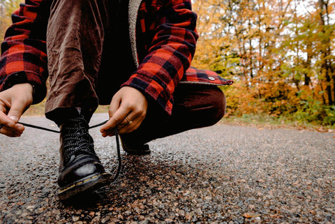 A man wearing boots and tying his shoelaces